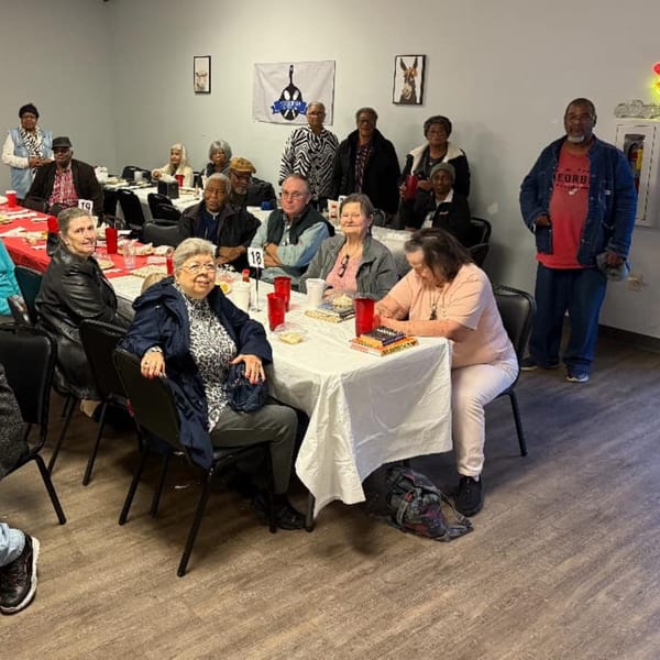 Diverse group of people gathered around tables with red cups at Southern Soul Cafe.