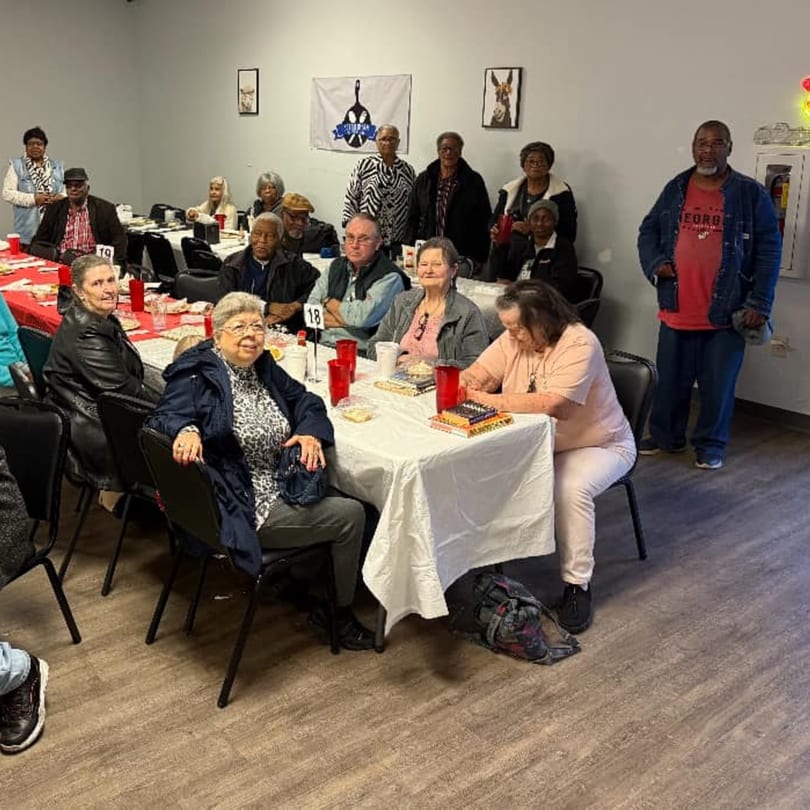 Diverse group of people gathered around tables with red cups at Southern Soul Cafe.