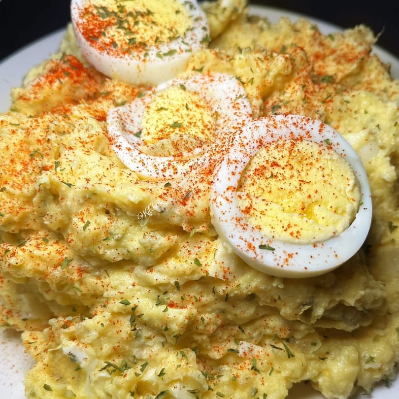 Creamy potato salad from Southern Soul Cafe, garnished with paprika, herbs, and hard-boiled egg slices.
