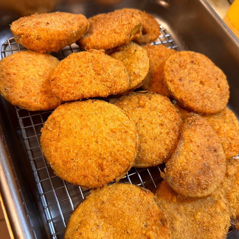 Golden-brown fried green tomatoes, a Southern Soul Cafe specialty, cooling on a wire rack.