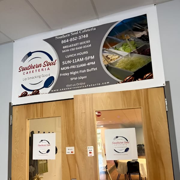 A large banner for Southern Soul Cafeteria with hours and a salad bar image, above wooden doors.
