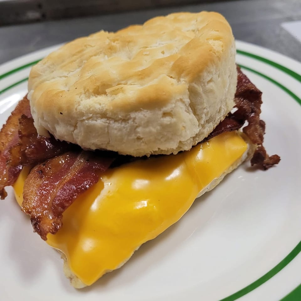 A Southern Soul Cafe bacon, egg, and cheese biscuit sandwich on a white plate with green stripes.